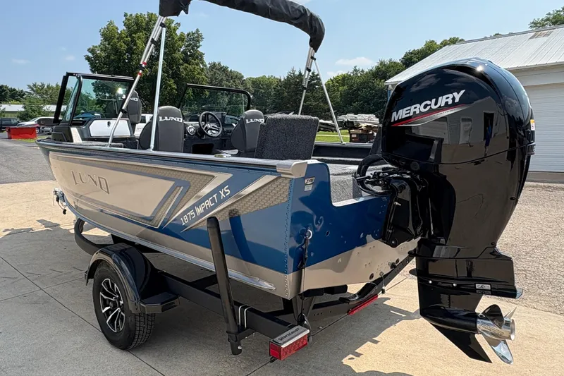 Slide: The Image of 2026 Lund 1875 Impact XS Sport boat with Mercury outboard motor, parked outdoors. - 4
