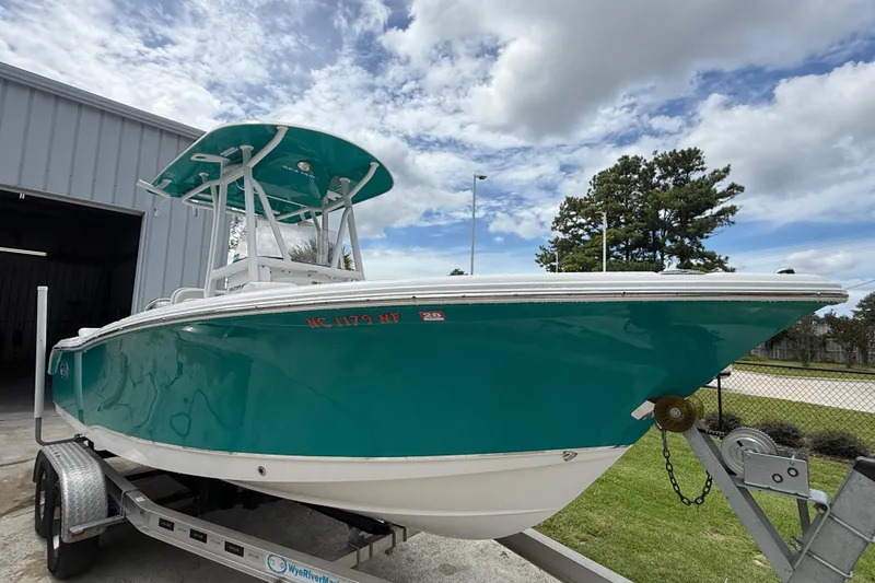 Slide: The Image of 2021 Sea Hunt Ultra 219 boat on trailer, teal color, parked outdoors. - 15