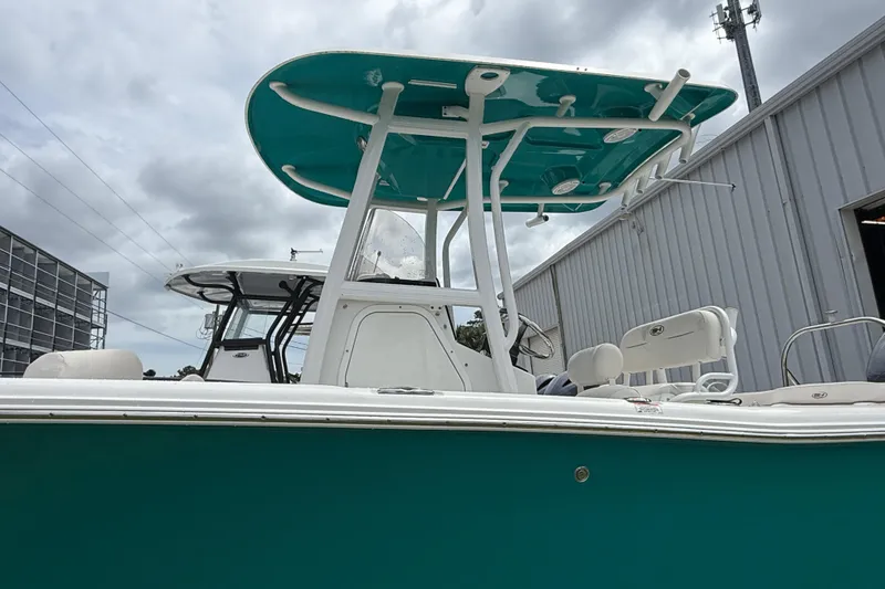Slide: The Image of 2021 Sea Hunt Ultra 219 boat with teal canopy, docked near a metal building. - 19