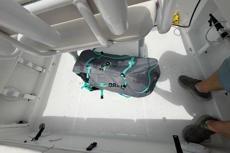 Slide: The Image of 2021 Sea Hunt Ultra 219 boat interior with a duffel bag and a person's leg visible. - 24