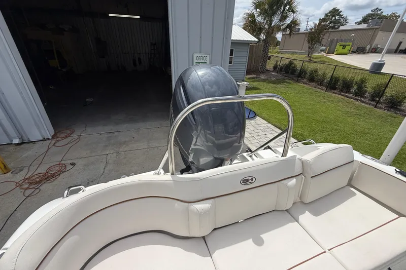 Slide: The Image of 2021 Sea Hunt Ultra 219 boat with outboard motor, parked near a building. - 26