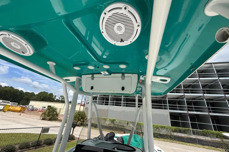 Slide: The Image of 2021 Sea Hunt Ultra 219 boat interior with teal ceiling and speakers, parked near construction site. - 31