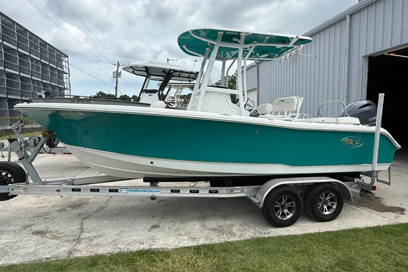 Slide: The Image of 2021 Sea Hunt Ultra 219 boat on trailer, teal hull, parked near a building. - 7