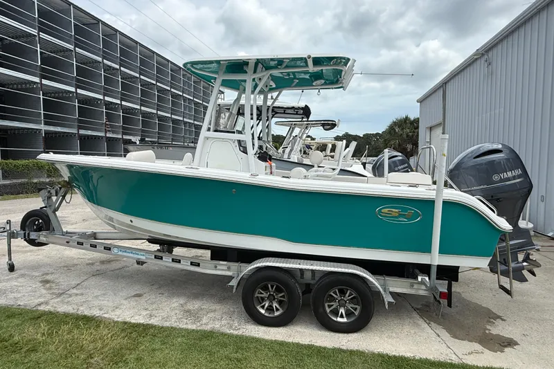 Slide: The Image of 2021 Sea Hunt Ultra 219 boat on trailer, teal hull, parked outdoors. - 8