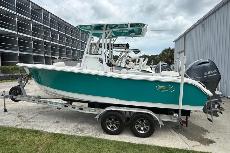 Slide: The Image of 2021 Sea Hunt Ultra 219 boat on trailer, teal hull, parked near storage facility. - 9