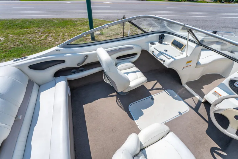 Slide: The Image of 2010 Stingray 195LX boat interior with white seating and dashboard, parked near a road. - 12