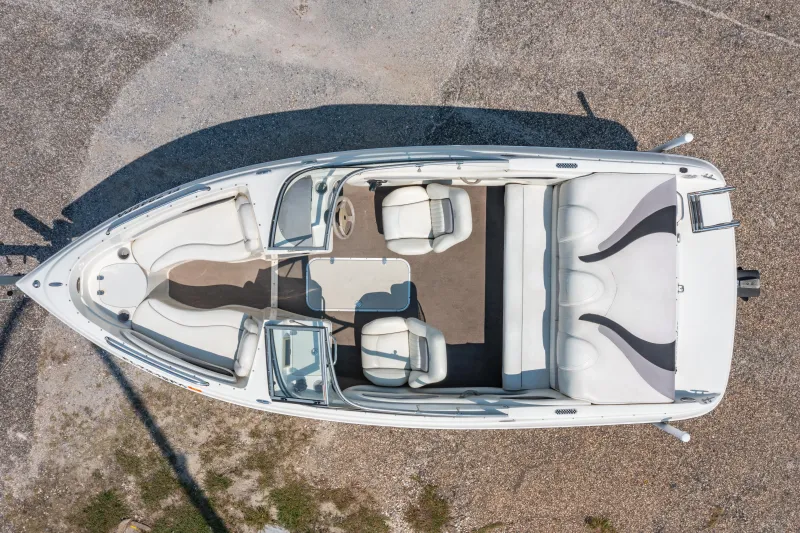 Slide: The Image of 2010 Stingray 195LX boat, aerial view, white interior, spacious seating, parked on gravel. - 20
