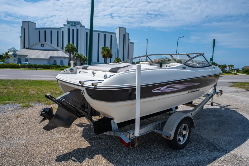 Slide: The Image of 2010 Stingray 195LX boat on trailer, parked near a large building under a blue sky. - 4