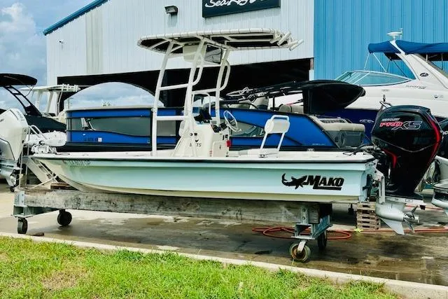 The Image of 2023 Mako 18 LTS boat on trailer, parked near blue building, side view. - 1