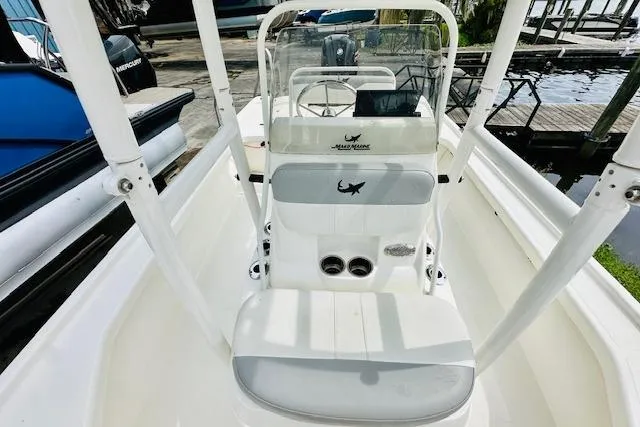 Slide: The Image of 2023 Mako 18 LTS boat interior with seating and console, docked near water. - 16