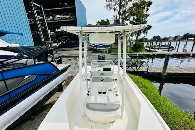 Slide: The Image of 2023 Mako 18 LTS boat docked near a marina with blue storage building. - 22