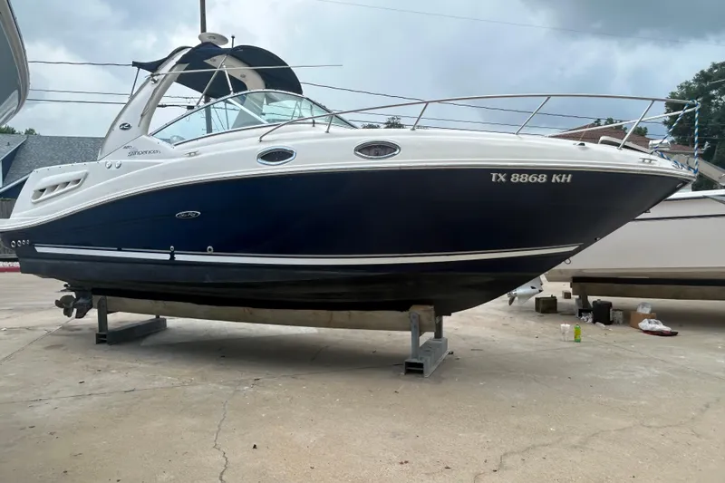 Slide: The Image of 2005 Sea Ray 260 Sundancer boat on dry dock, blue and white exterior. - 6