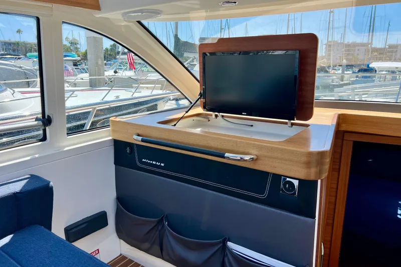 Slide: The Image of Interior of 2018 Nimbus 365 Coupe with TV, wooden accents, and marina view. - 85