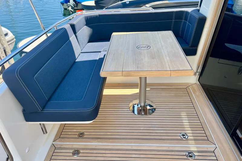 Slide: The Image of Luxurious seating area on a 2018 Nimbus 365 Coupe yacht with wooden table and blue cushions. - 46