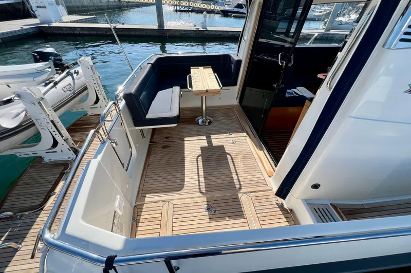 Slide: The Image of Nimbus 365 Coupe 2018 boat deck with seating and table, docked at marina. - 37