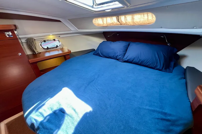 Slide: The Image of Cozy cabin interior of 2018 Nimbus 365 Coupe with blue bedding and wooden accents. - 129