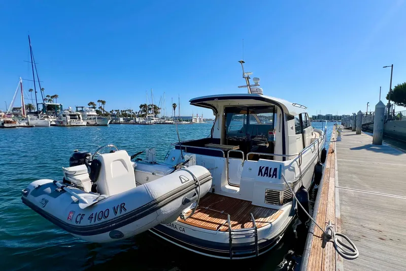 Slide: The Image of Nimbus 365 Coupe 2018 docked with inflatable boat, sunny marina backdrop. - 12