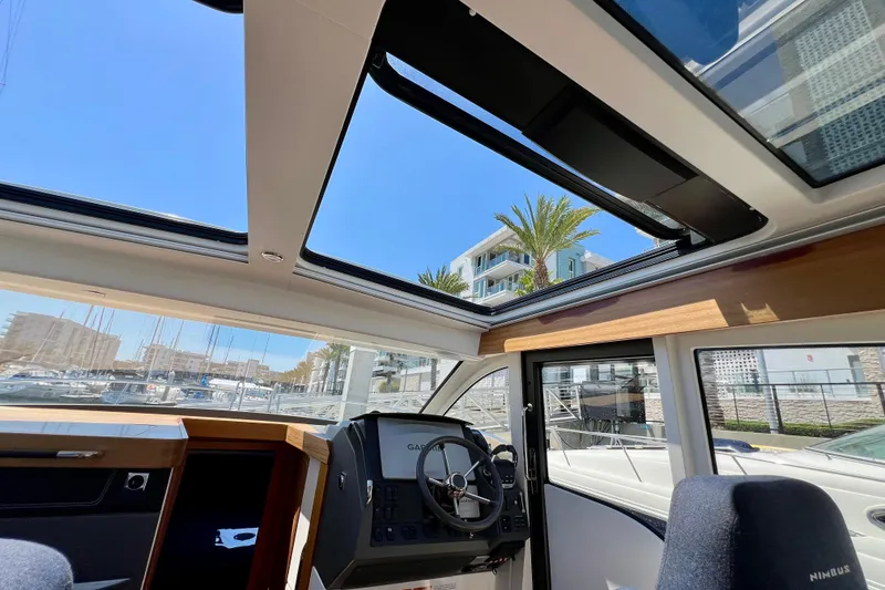 Slide: The Image of Interior view of 2018 Nimbus 365 Coupe boat with open sunroof and marina backdrop. - 91