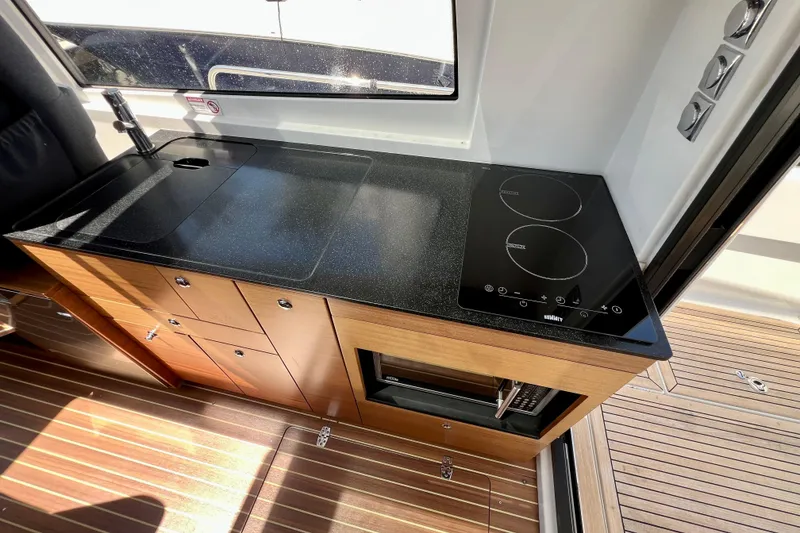 Slide: The Image of Modern kitchen area in 2018 Nimbus 365 Coupe with sleek black countertop and stove. - 104