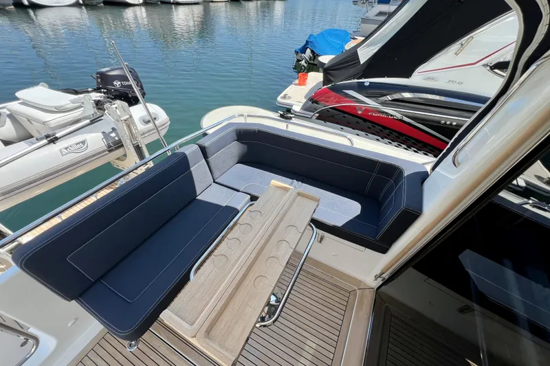 Slide: The Image of 2018 Nimbus 365 Coupe yacht with elegant seating and wooden table, docked at marina. - 43