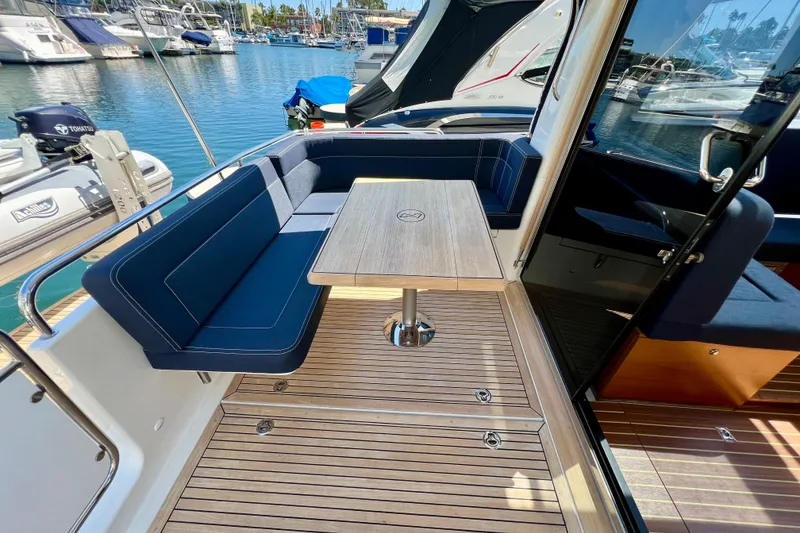 Slide: The Image of 2018 Nimbus 365 Coupe yacht with elegant seating and wooden deck in a marina setting. - 45