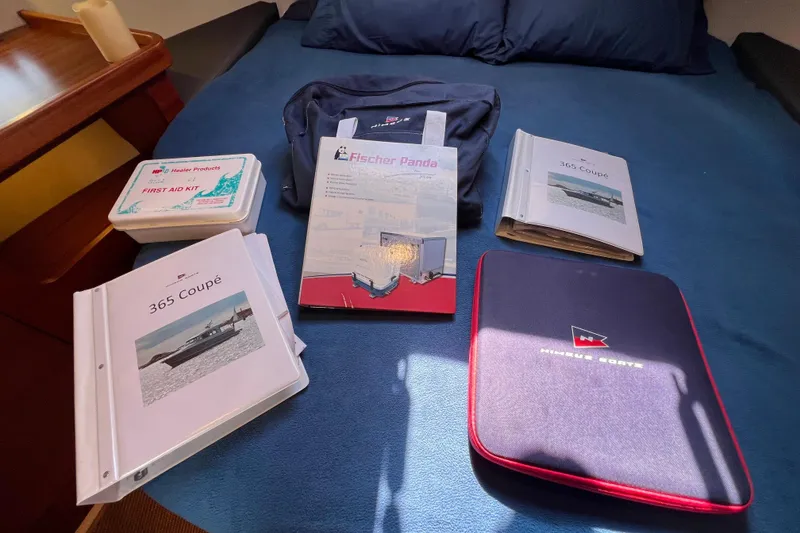 Slide: The Image of Nimbus 365 Coupe 2018 manuals and first aid kit on a blue bedspread. - 131