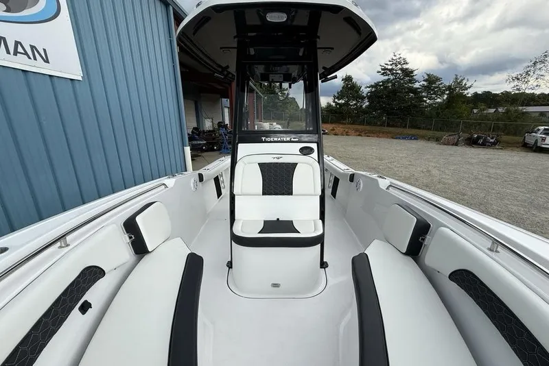 Slide: The Image of 2026 Tidewater 232 CC Adventure boat interior with seating and console, parked outdoors. - 26