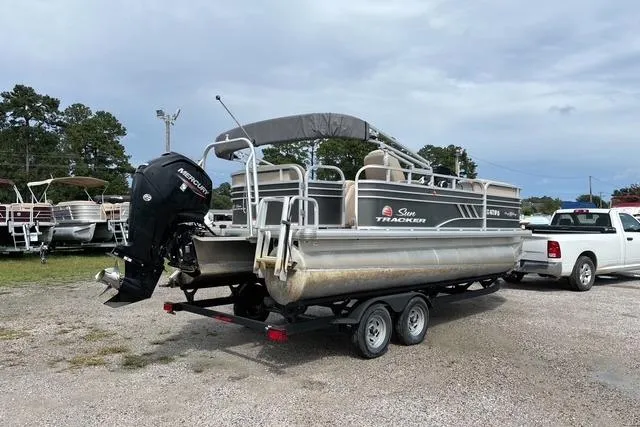 Slide: The Image of 2021 Sun Tracker Party Barge 20 DLX pontoon boat on trailer, parked outdoors. - 2
