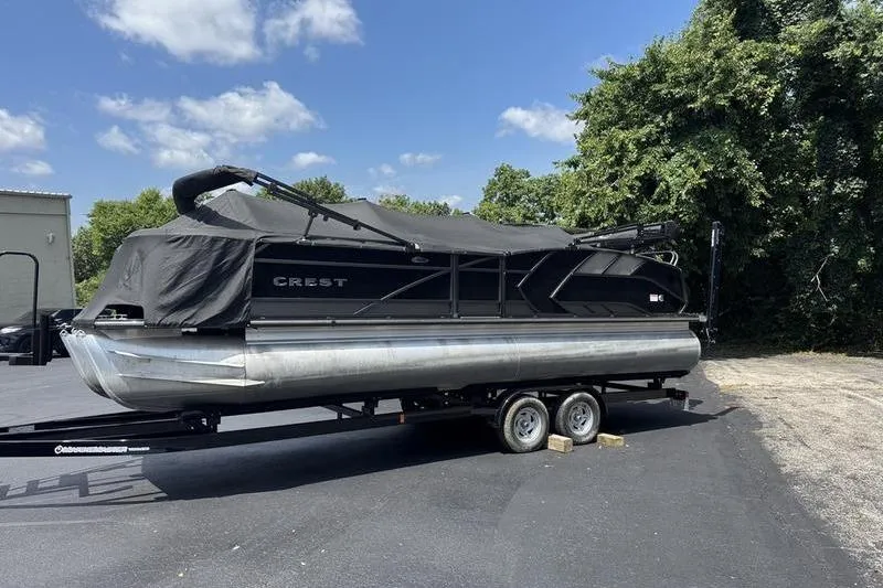Slide: The Image of 2020 Crest Caribbean LX 250 SLC pontoon boat on trailer, covered, outdoors. - 1