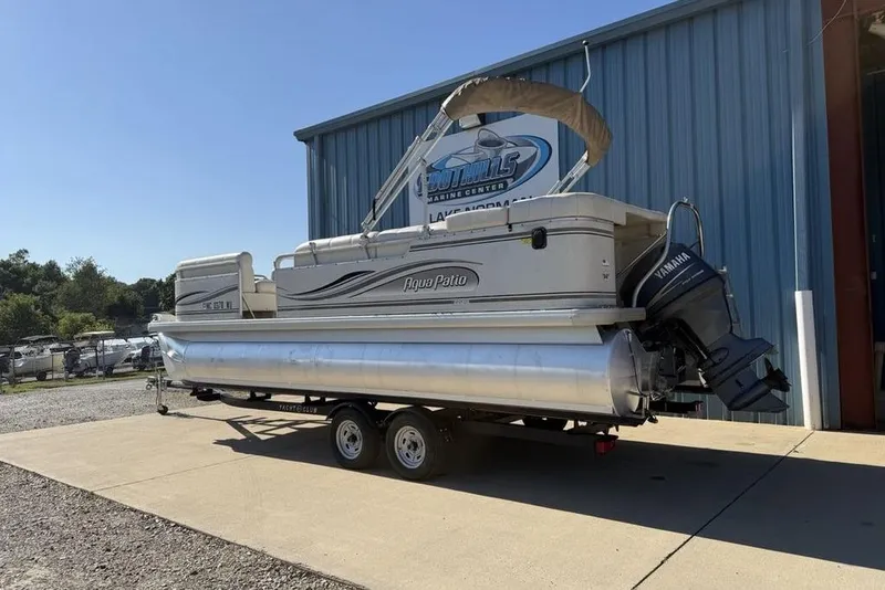 Slide: The Image of 2002 Godfrey AP220RS pontoon boat on trailer, parked outside a marine center. - 6
