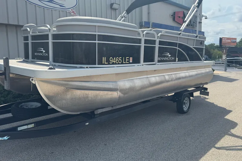 Slide: The Image of 2023 Bennington 20 SL pontoon boat on trailer, parked outdoors. - 2
