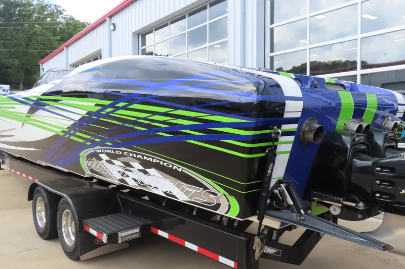 Slide: The Image of 2007 Outerlimits 44 GTX powerboat with vibrant green and blue graphics on a trailer. - 10