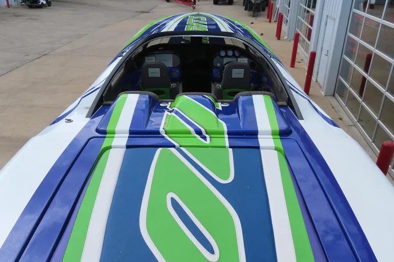 Slide: The Image of 2007 Outerlimits 44 GTX speedboat with vibrant blue and green design, docked at marina. - 12