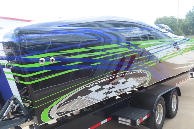 Slide: The Image of 2007 Outerlimits 44 GTX powerboat with vibrant blue and green graphics on a trailer. - 6