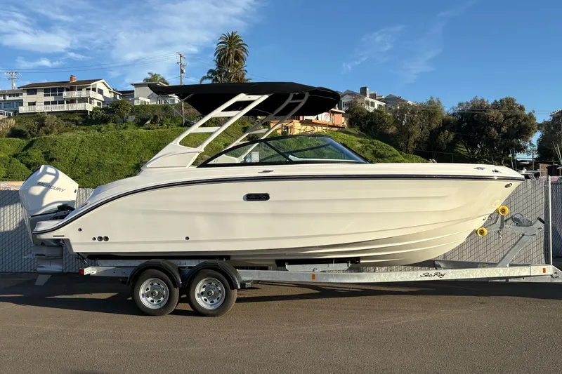 The Image of 2026 Sea Ray SDX 230 Outboard boat on trailer, parked near residential area. - 0