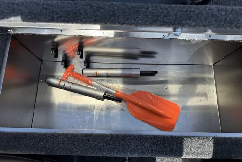 Slide: The Image of Storage compartment in 2026 Tracker BASS TRACKER® Classic XL with orange paddle and tools. - 17