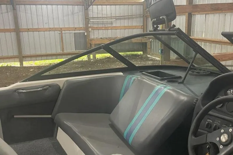 Slide: The Image of 1998 Malibu Response boat interior with gray seating and teal stripes in a metal shed. - 3