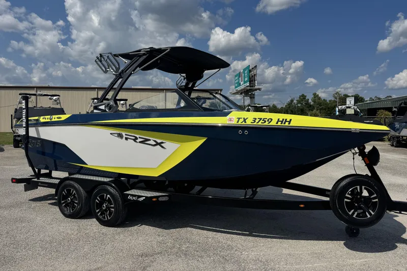 The Image of 2020 Tigé 22RZX boat on trailer, blue and yellow design, parked outdoors. - 0