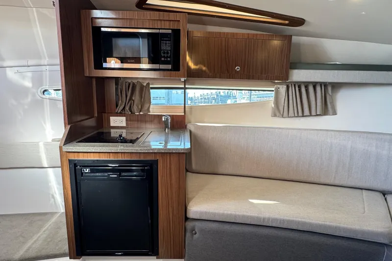 Slide: The Image of 2020 Four Winns Vista 275 interior with kitchenette, microwave, and seating area. - 14