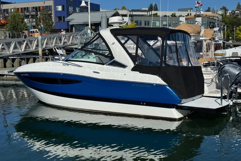 Slide: The Image of 2020 Four Winns Vista 275 boat docked in a marina, featuring a sleek blue and white design. - 2