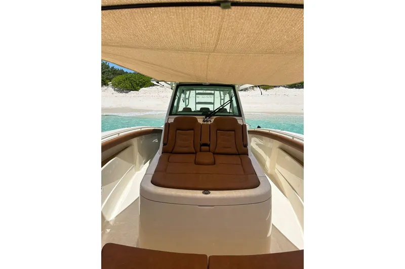 Slide: The Image of 2019 Scout 420 LXF boat interior with sunshade, anchored near a sandy beach. - 29