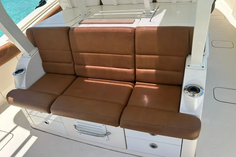 Slide: The Image of Brown leather seating on 2019 Scout 420 LXF boat, featuring cup holders and storage. - 31