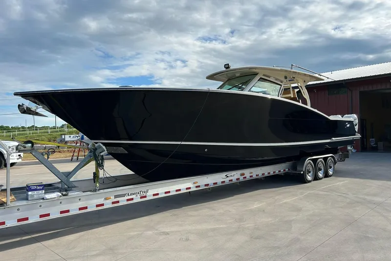 Slide: The Image of 2019 Scout 420 LXF boat on trailer, parked outdoors under cloudy sky. - 4