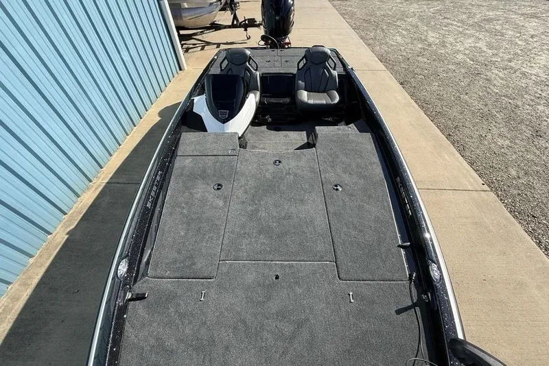 Slide: The Image of 2026 Skeeter ZXR20 SE boat with spacious deck and seating, parked near a blue building. - 26