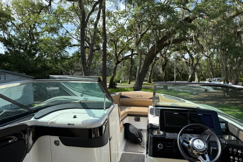 Slide: The Image of 2023 Sea Ray SLX 260 Outboard boat interior with modern dashboard and seating, surrounded by trees. - 15