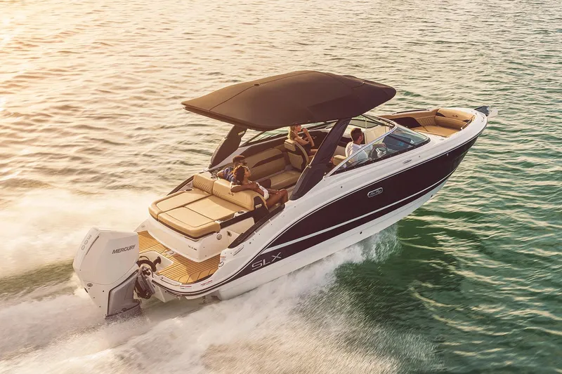 Slide: The Image of 2023 Sea Ray SLX 260 Outboard cruising on water at sunset. - 5