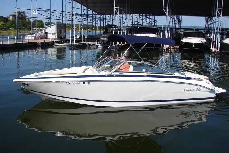 Slide: The Image of 2011 Cobalt 232 boat docked in a marina, featuring a sleek white design. - 2