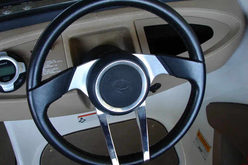 Slide: The Image of Steering wheel of a 2011 Cobalt 232 boat with dashboard controls. - 30