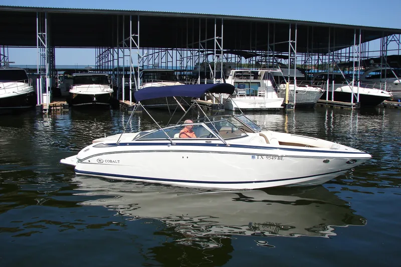 Slide: The Image of 2011 Cobalt 232 boat docked in marina, featuring sleek design and blue canopy. - 4