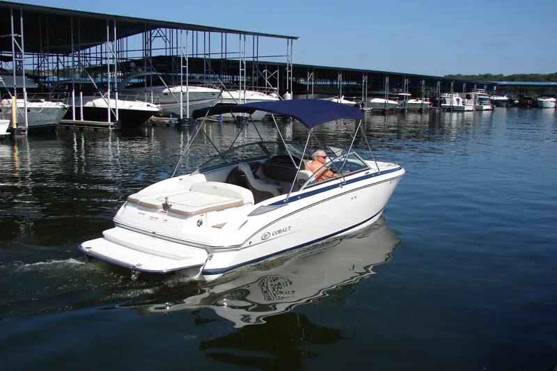 Slide: The Image of 2011 Cobalt 232 boat cruising near marina with covered docks in the background. - 6